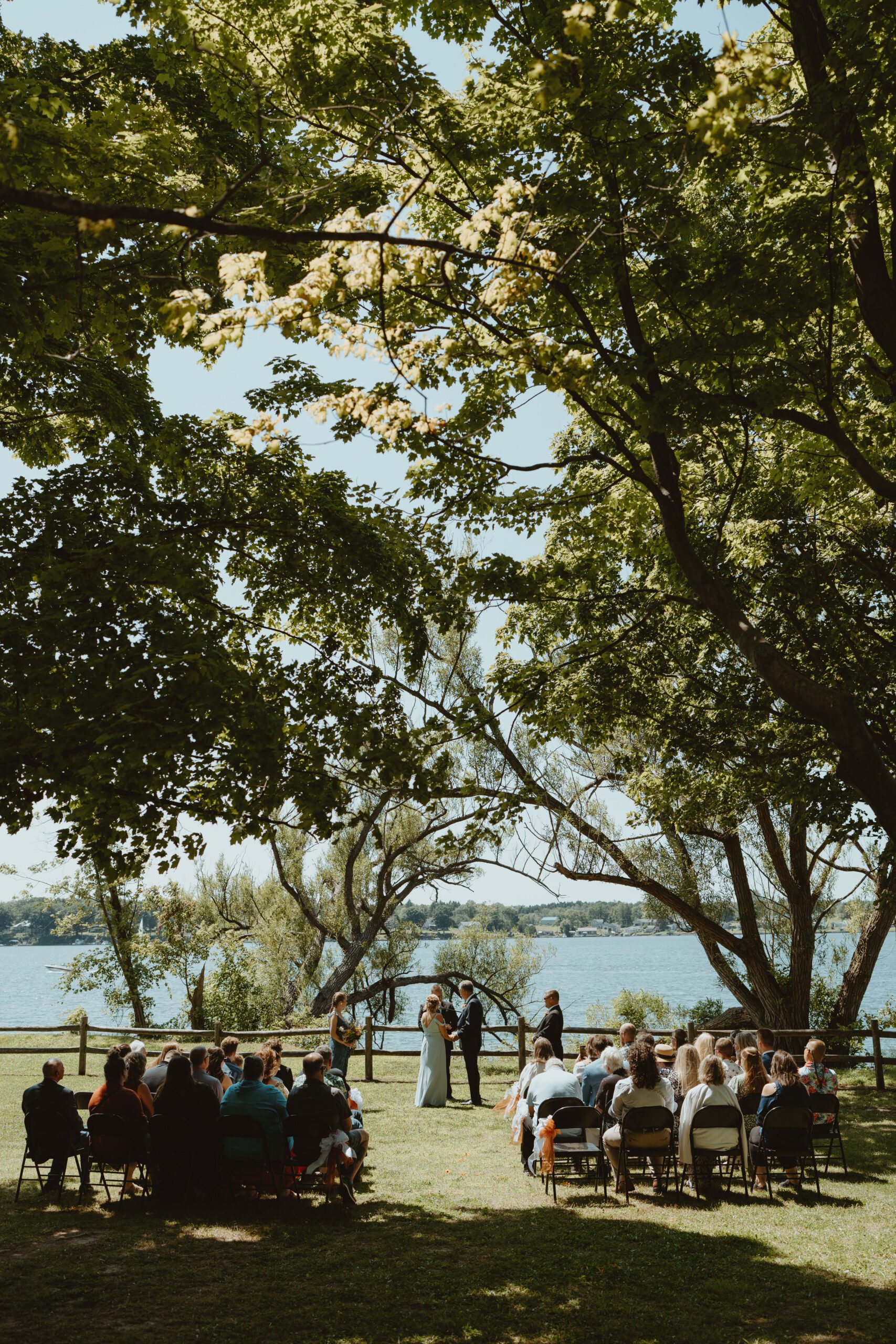 Bride and groom seated on a stone pier at Fair Haven State Park with soft lake reflections in the background during golden hour.