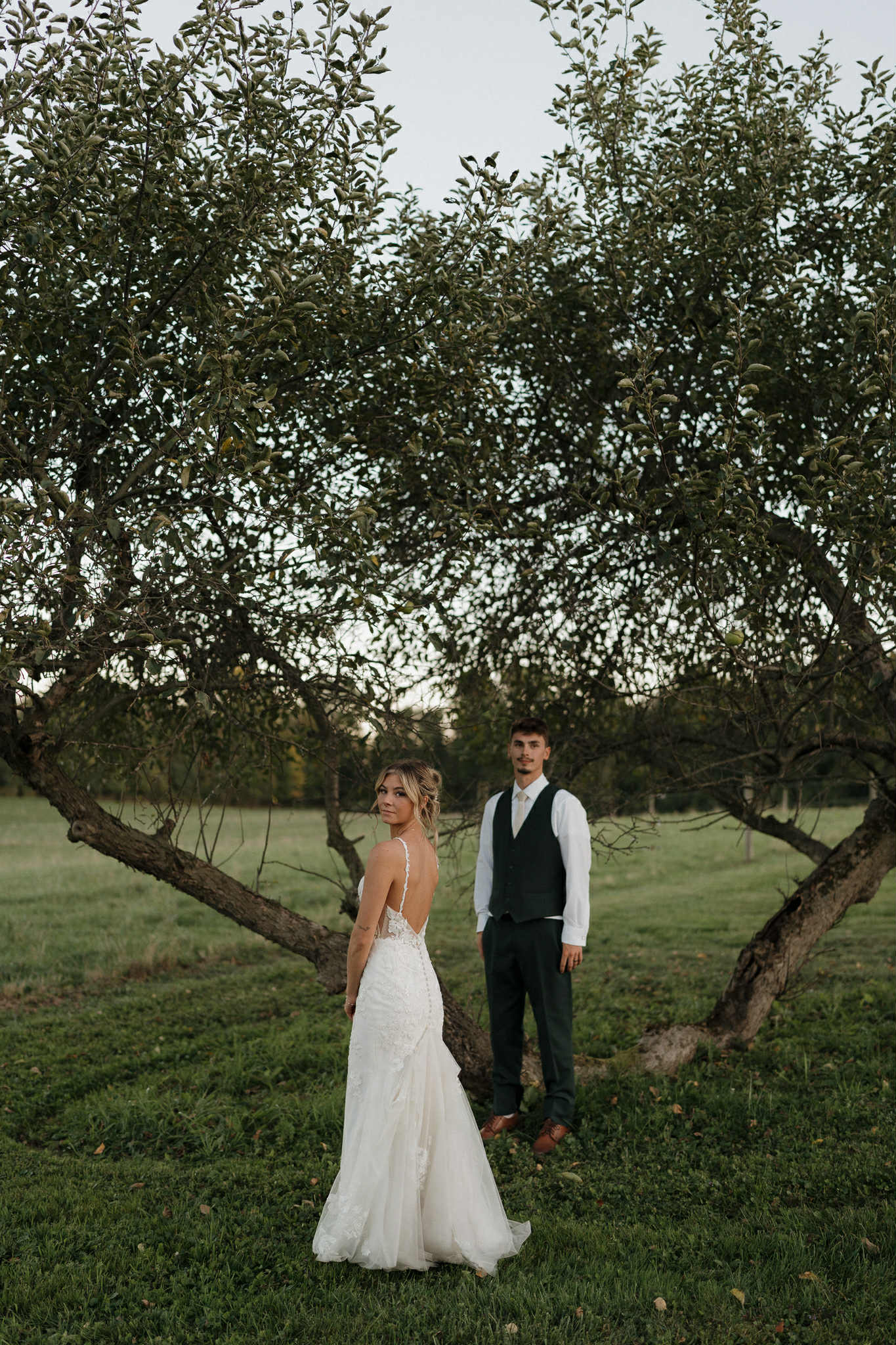Bride and groom standing by the pond at Old Hickory Farm in Weedsport, NY, surrounded by pampas grass and rustic fall tones of rust and hunter green.