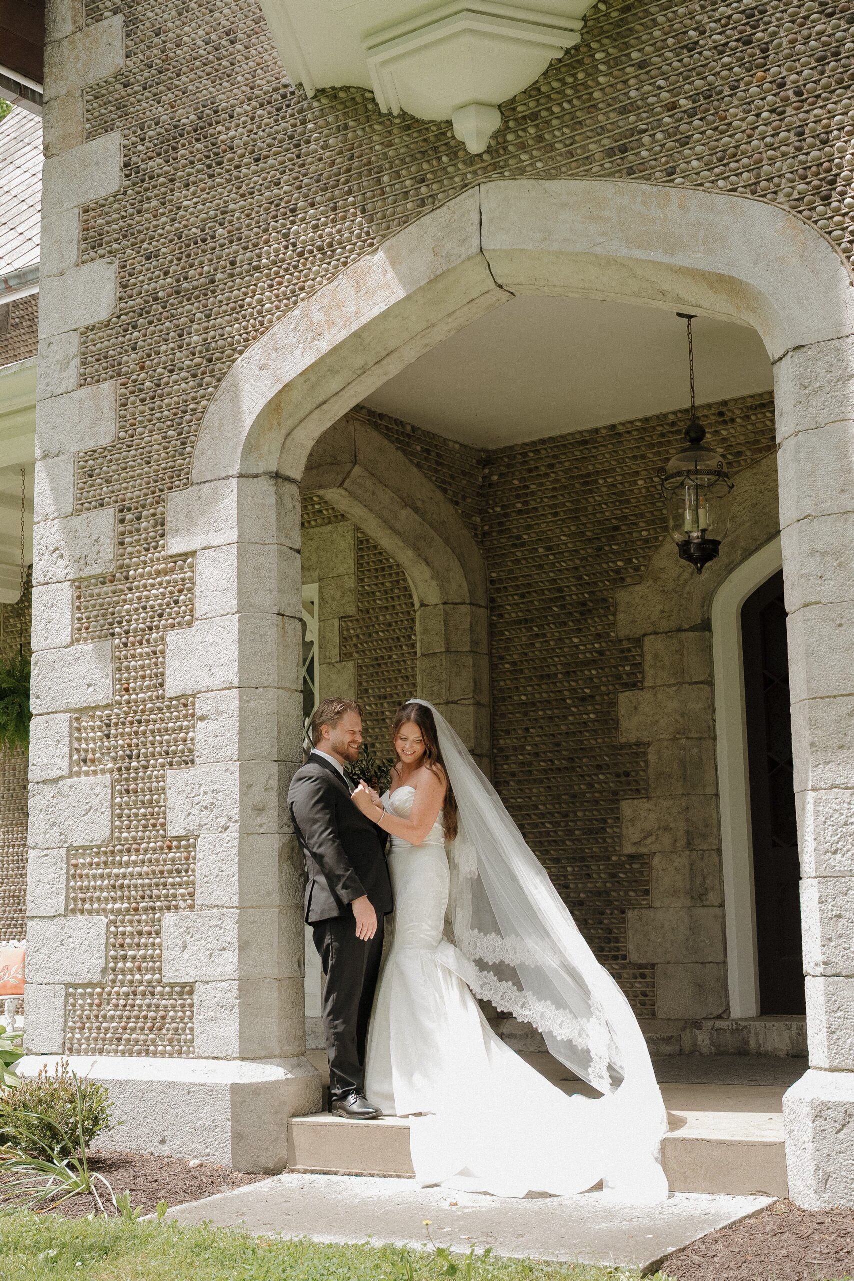 Greg and Lynsey walk beside the pond and weeping willow at their Munro House wedding in Jordan, New York.